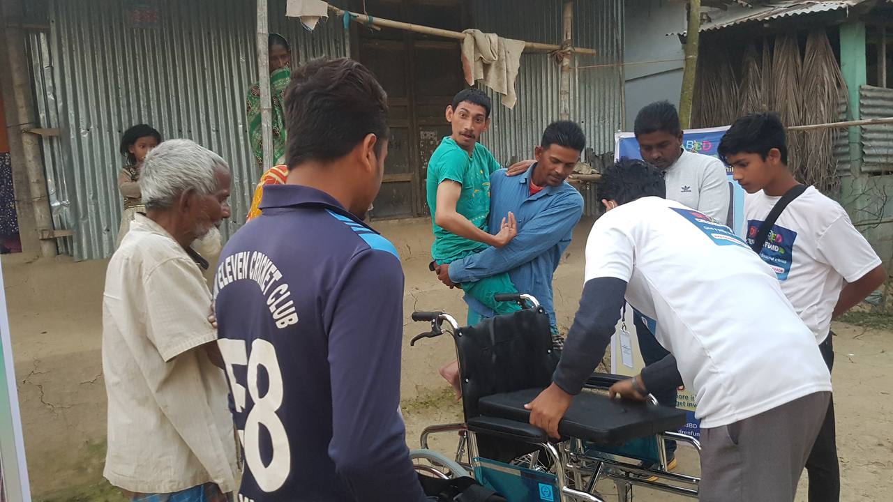 DCF team helping a child into a new wheelchair during a delivery in Sylhet